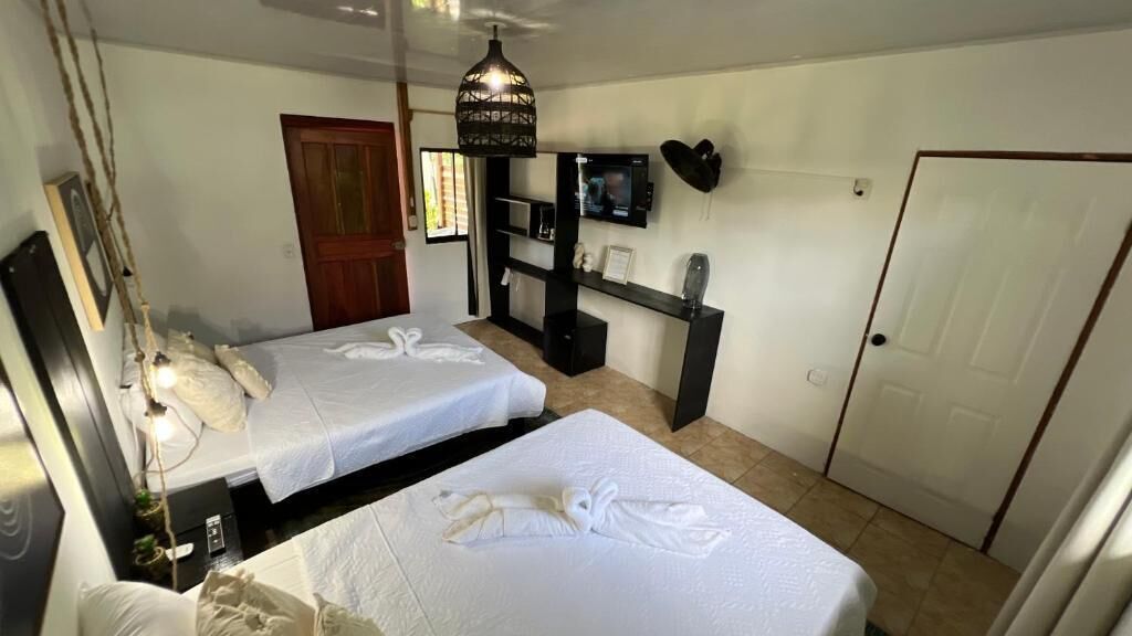 Hotellihuone, jossa on kaksi sänkyä, televisio, työpöytä ja vaatekaappi.