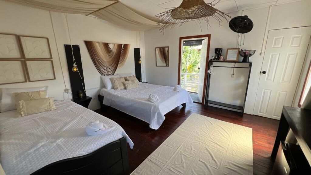 A bedroom with two beds, a small kitchenette, and a door leading to a balcony.