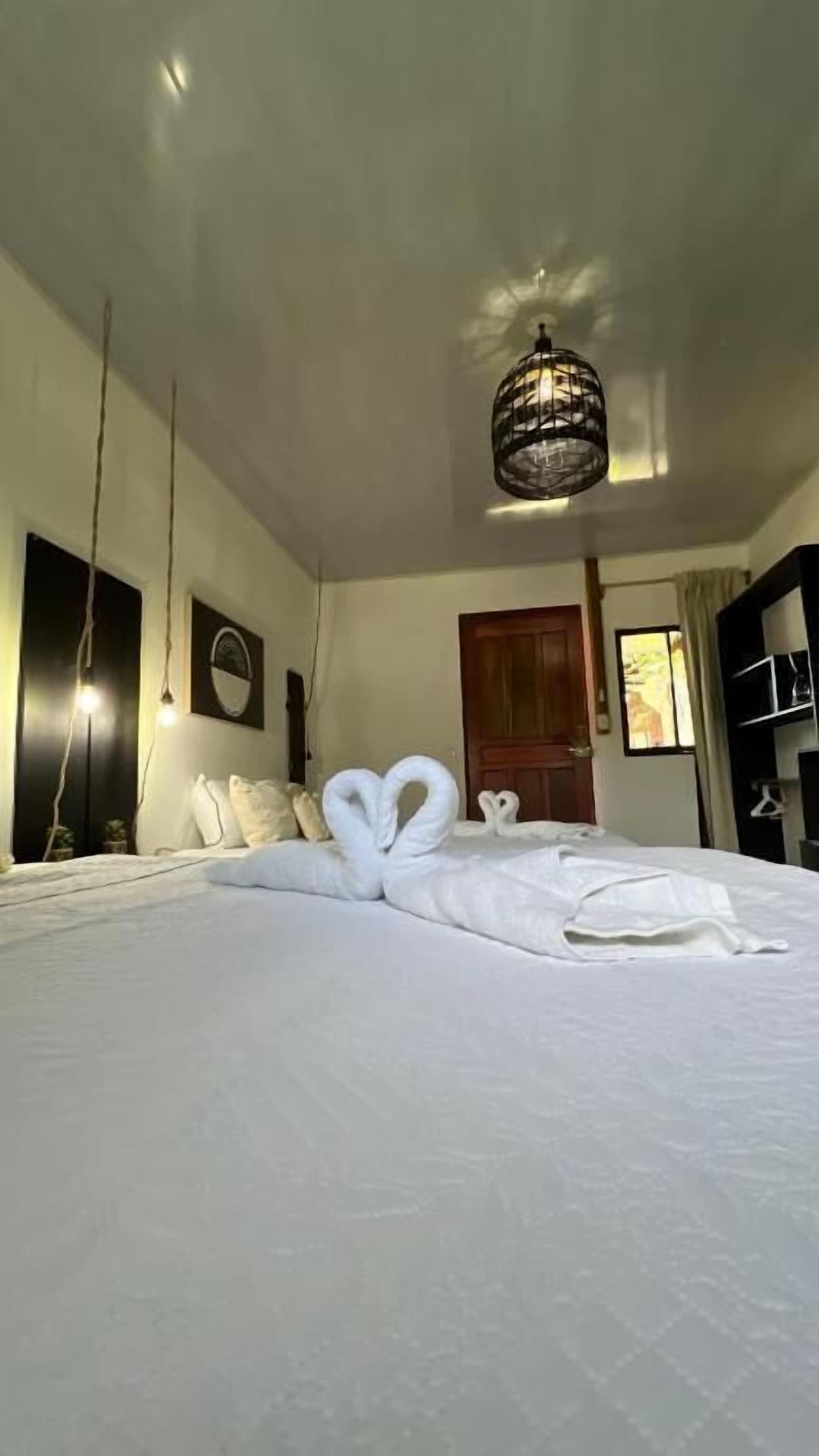 Una camera d'albergo con un letto grande, un lampadario, una porta in legno e un armadio.