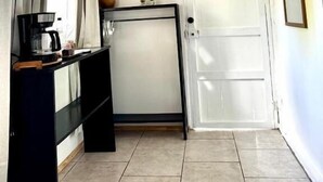 Una habitación pequeña y funcional con kitchenette, una puerta y un cuadro en la pared.