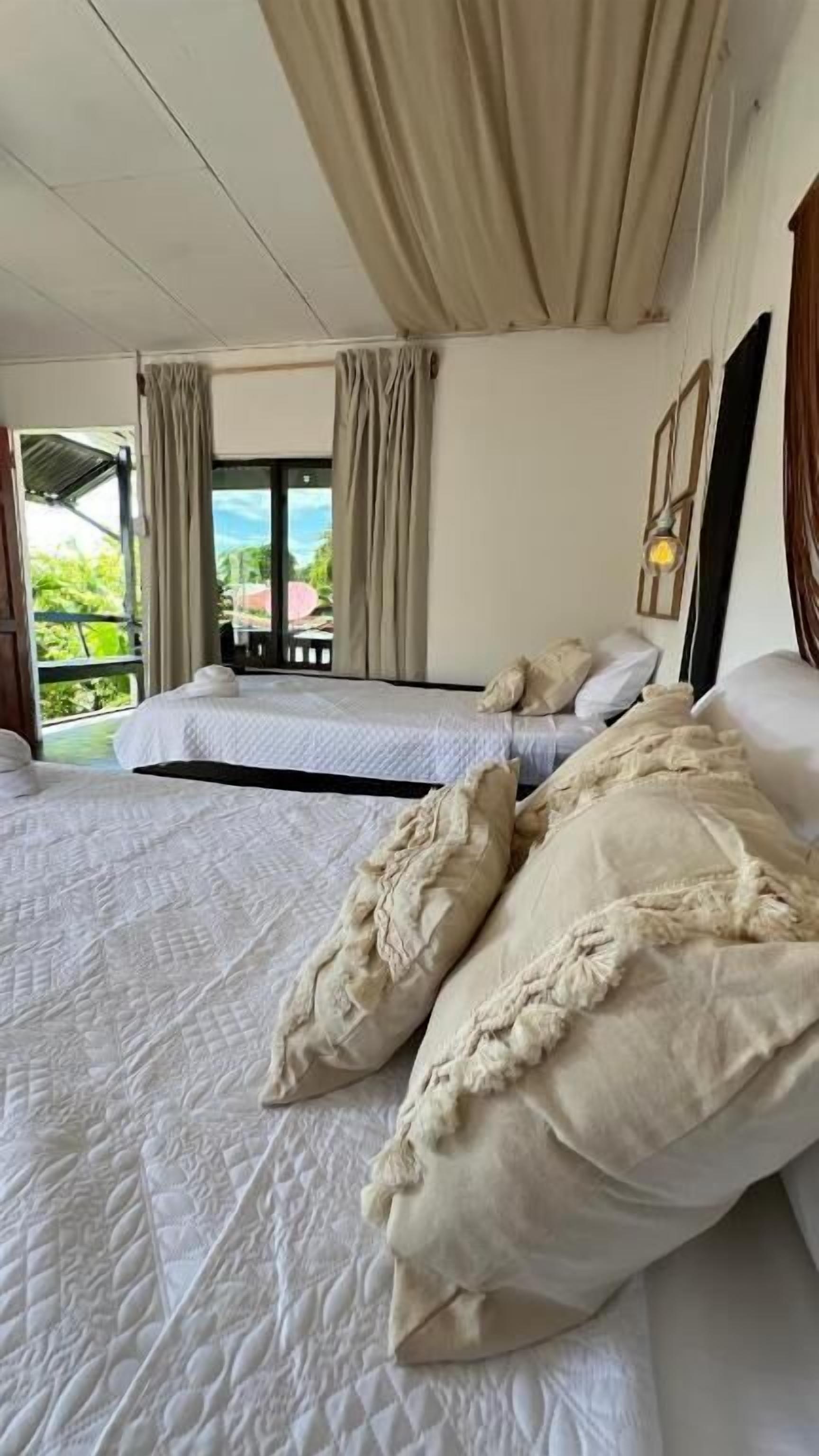 A bedroom with two beds, a balcony, and curtains.