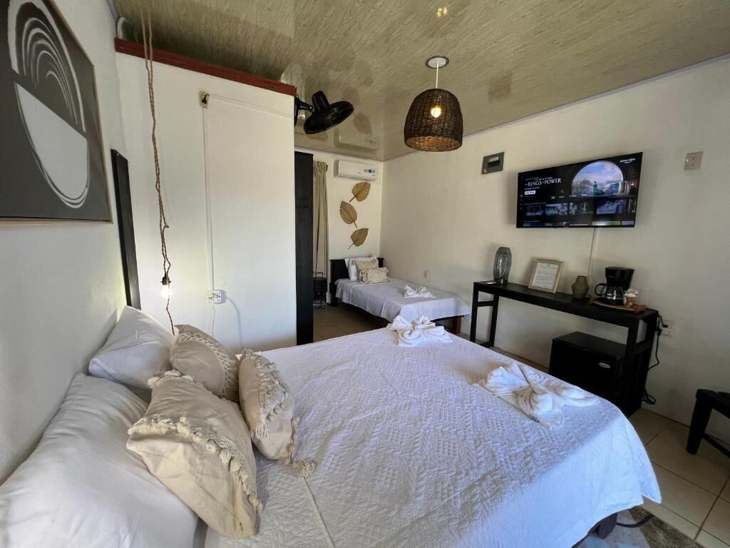 A hotel room with a large bed, a desk with a computer, a television, and a wall-mounted artwork.