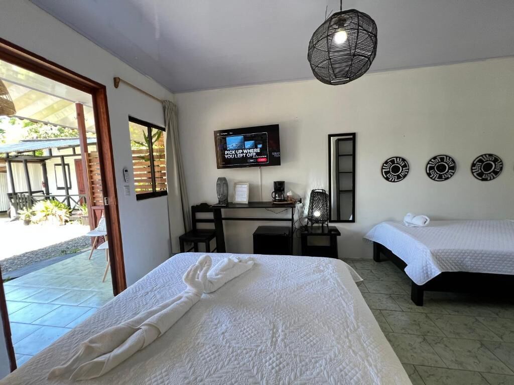 A hotel room with a bed, a desk, a television, and a balcony.