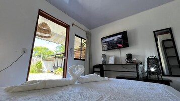 Habitación de hotel con cama, televisor en la pared, cafetera y vistas al exterior.