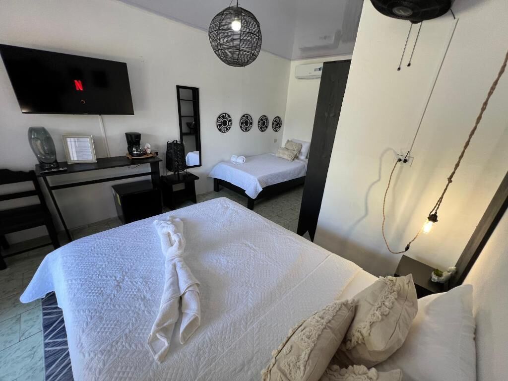 Una habitación de hotel con cama, escritorio, televisor y estante en la pared.
