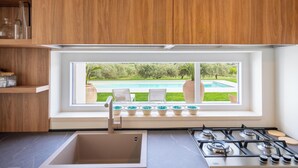 Une cuisine avec une fenêtre donnant sur une piscine et un jardin.