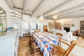 Ein Essbereich mit einem langen Tisch, Stühlen, einer Treppe und einem Kamin.