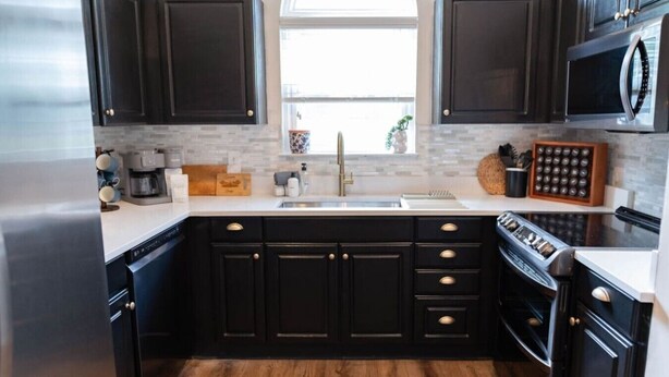 A modern kitchen with dark cabinetry, a stainless steel refrigerator, a microwave, and a built-in oven.