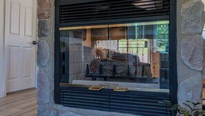 A stone fireplace with a glass door, a wooden bench, and a door to the left. - Cozy Cabin - walk to creek - Close to Sedona (Rimrock)
