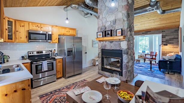 A modern kitchen with stainless steel appliances, wooden cabinets, and a stone fireplace. - Cozy Cabin - walk to creek - Close to Sedona (Rimrock)