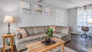 A living room with a sofa, coffee table, lamp, and artwork on the wall.