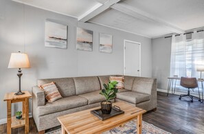 A living room with a sofa, coffee table, lamp, and artwork on the wall.