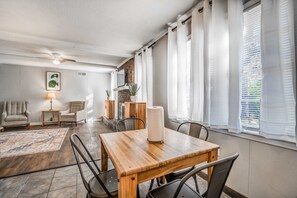 A dining area with a wooden table, chairs, a lamp, and a rug.
