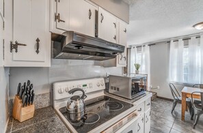 A kitchen with a stove, microwave, and cabinets.