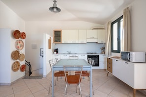 Une cuisine moderne avec une table à manger, des chaises et un four à micro-ondes.