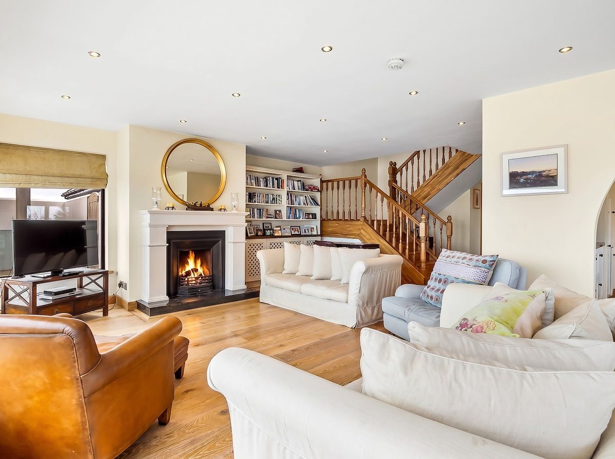 A living room with a fireplace, a television, and a staircase.