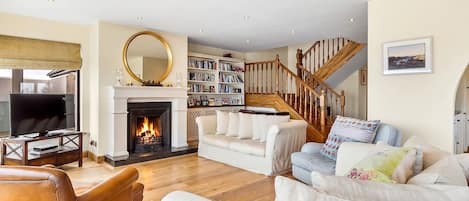 A living room with a fireplace, a television, and a staircase.