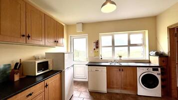 Una cocina funcional con muebles de madera, microondas, lavavajillas y lavadora.