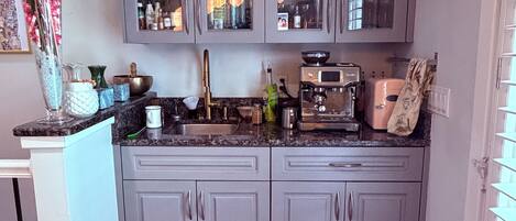 A kitchen with grey cabinets, a wooden floor, and a variety of kitchen appliances.