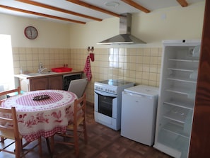 Une cuisine équipée d’une table à manger, d’un four, d’un réfrigérateur et d’une horloge murale.