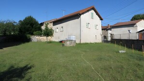 Un bâtiment à deux étages, doté d’un toit en pente, d’un mur en pierre et d’une cour gazonnée.