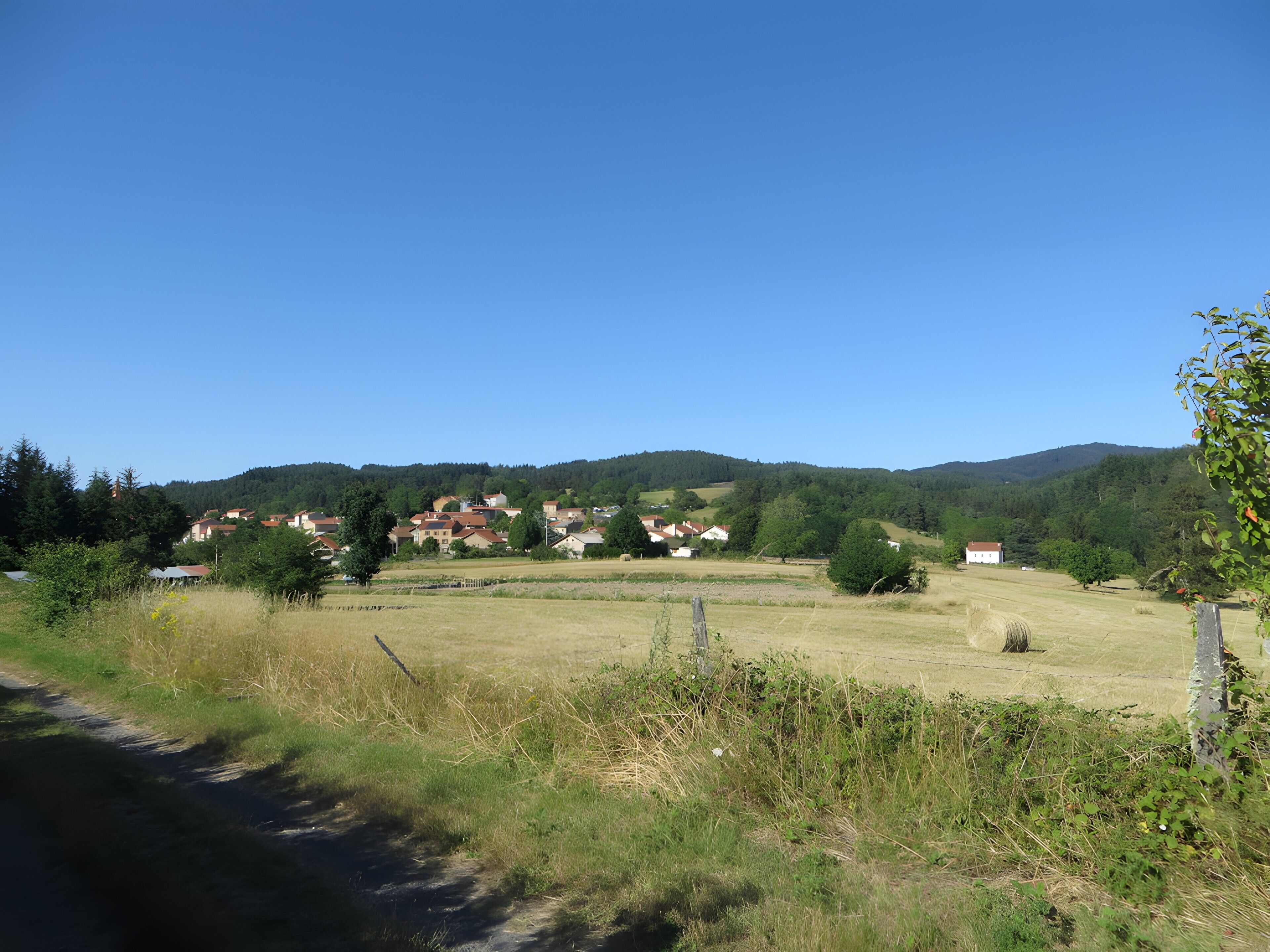 A rural landscape with houses, a clear sky, and a road.