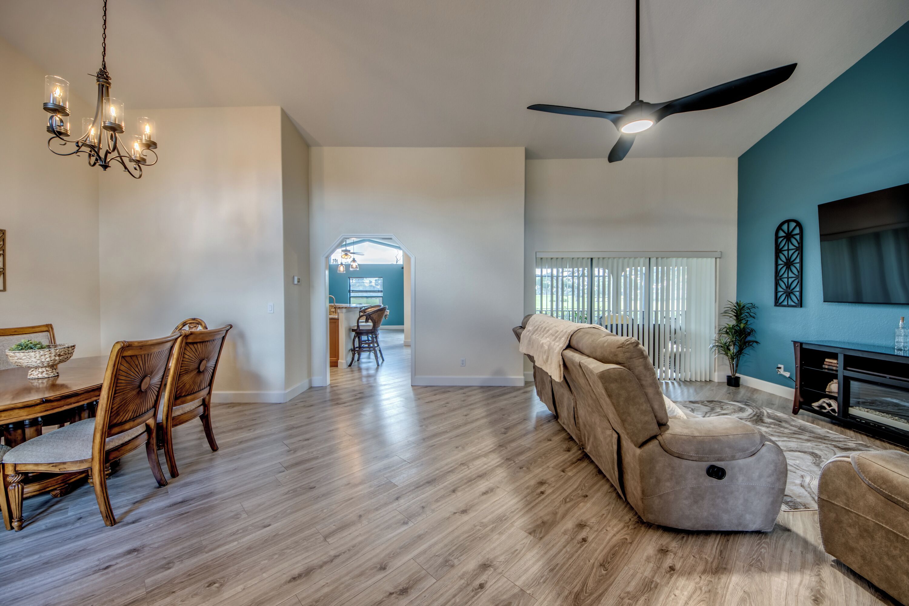 A spacious living room with a ceiling fan, a dining area with wooden chairs, and a modern fireplace.