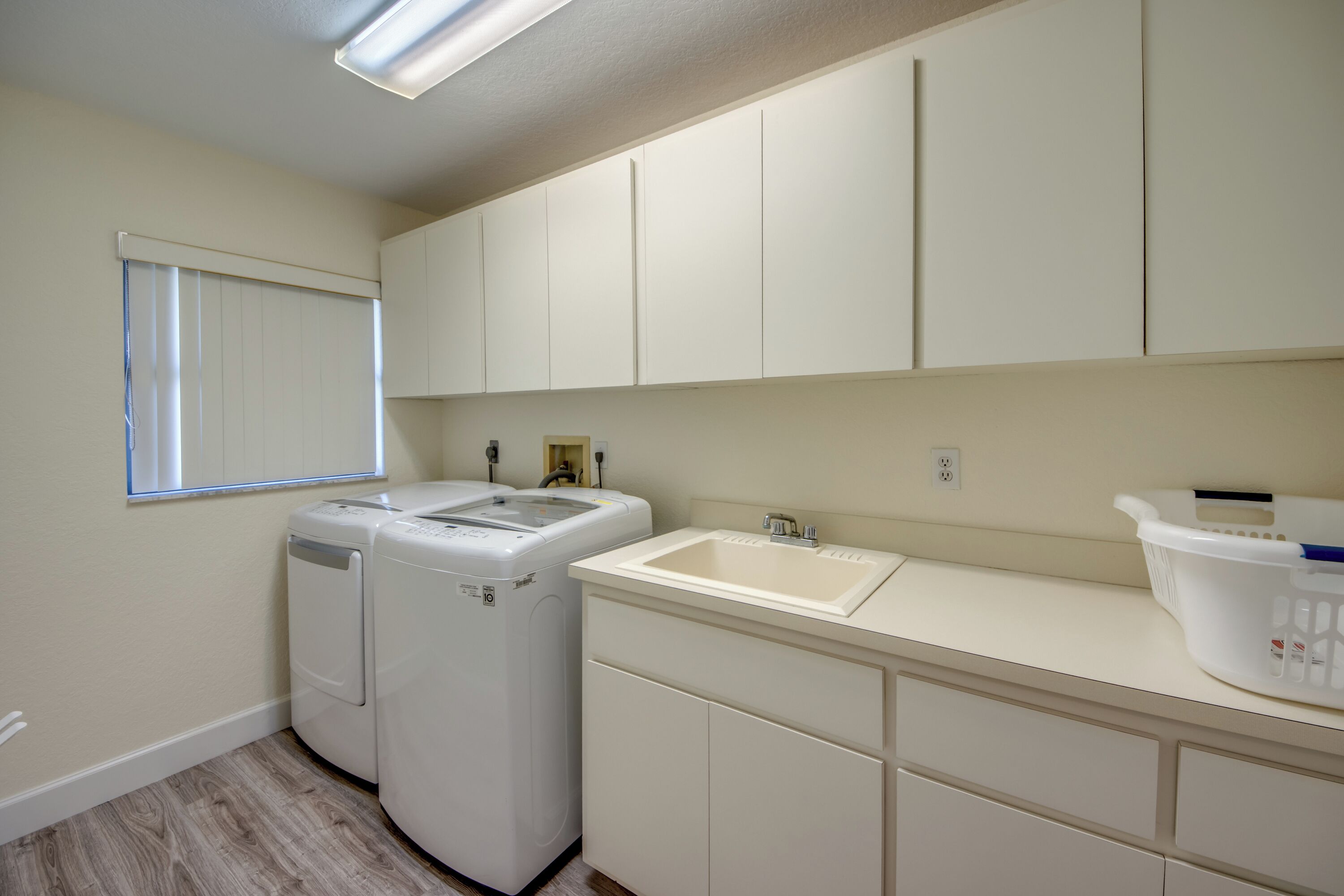 A laundry room with two washing machines, a sink, and a window.