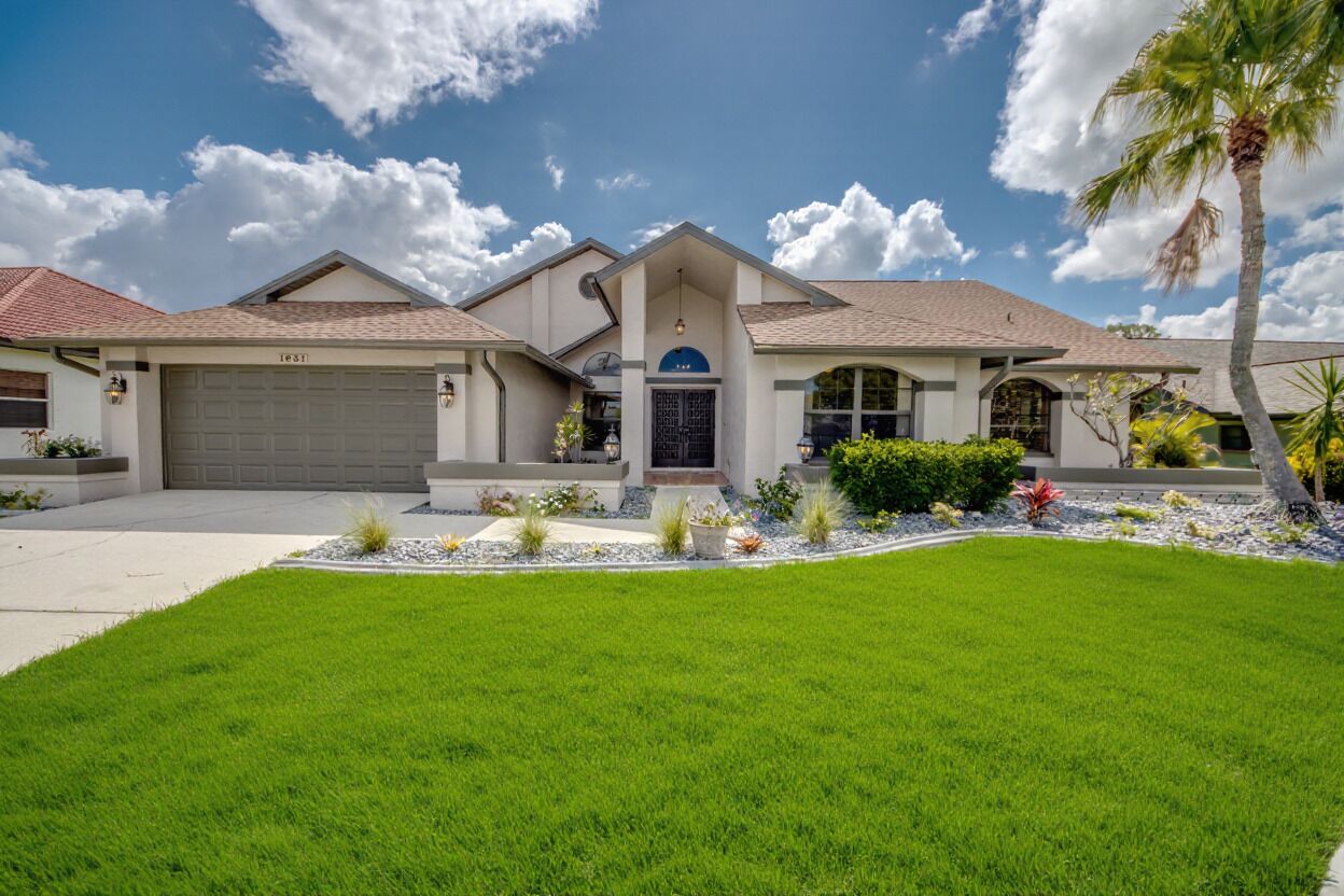 A modern two-story house with a garage, a well-maintained lawn, and a variety of plants.
