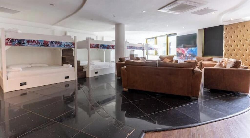 A hotel room with bunk beds, a sofa, and a large TV.