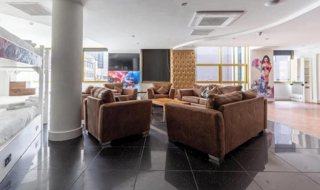 A modern living room with a sofa set, a large window, and a painting on the wall.