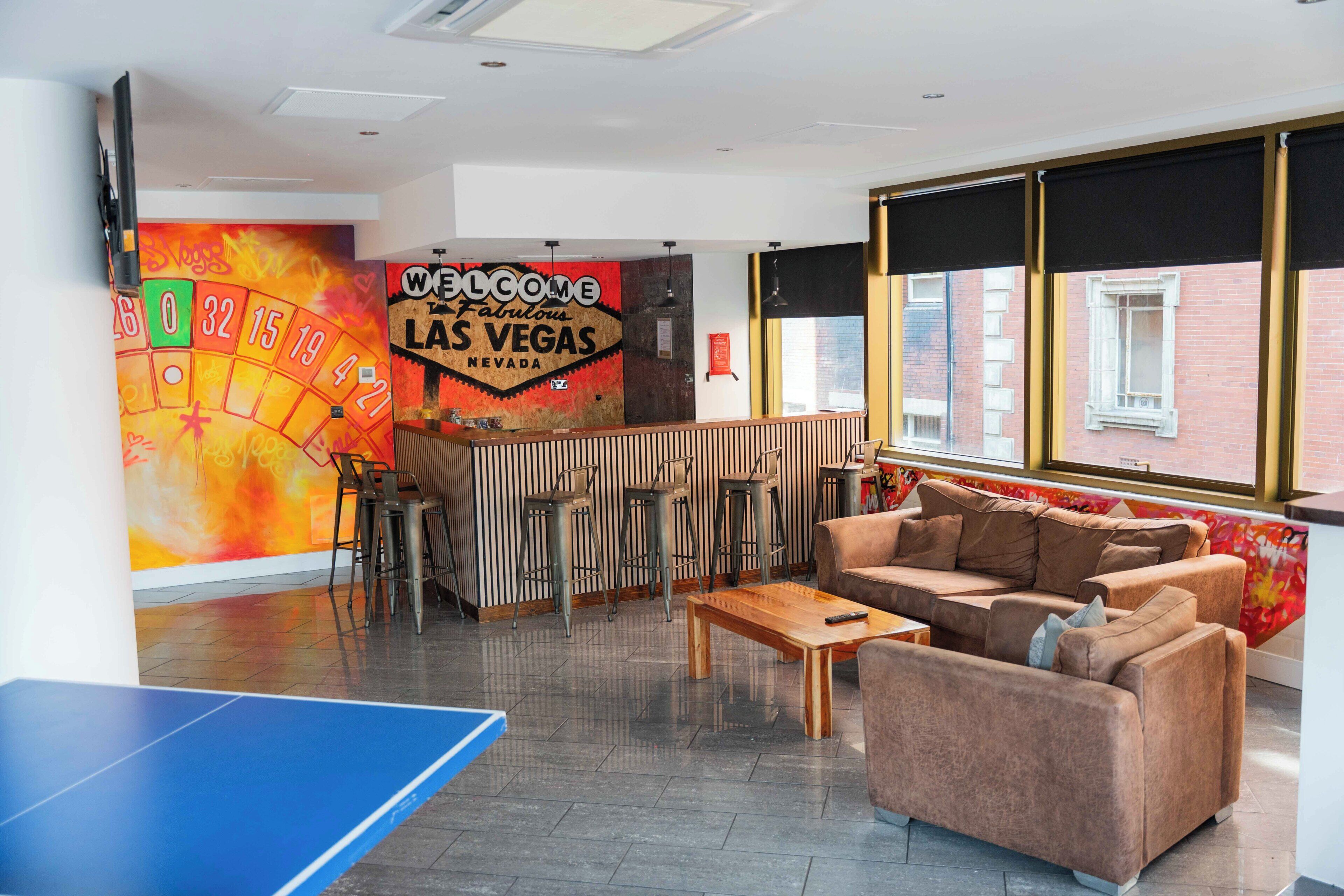 A room with a roulette wheel, a couch, a coffee table, and a ping pong table.