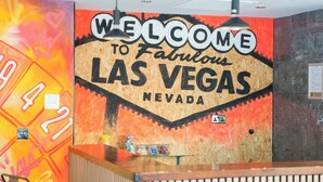 Ein Empfangsbereich mit einem Schild, auf dem 'Welcome to Fabulous Las Vegas Nevada' steht, einem Empfangstisch und einer Wand mit einem farbenfrohen Design.