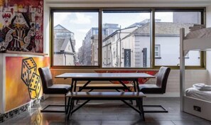 A room with a large window, a wooden table with benches, and a bed. - Las Vegas Party Pad (Sleeps 16) (Liverpool)