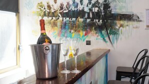 Eine Bar mit einer Champagnerflasche in einem Kübel, zwei leere Gläser und einem Wandgemälde.