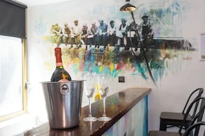 A bar area with a bottle of champagne in a bucket, two empty glasses, and a mural on the wall. - New York Party Pad (Sleeps 16) (Liverpool)