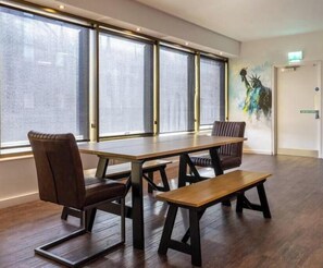 A conference room with a large table, two chairs, and a bench. - New York Party Pad (Sleeps 16) (Liverpool)