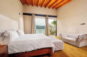 Une chambre avec un lit, un canapé, une vue sur l’extérieur et un plafond en bois.