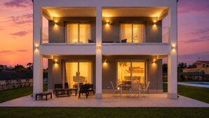 A modern two-story house with a balcony, a patio with outdoor furniture, and a pool in the background. - Zaffiri House - Elegant villa with private pool 300 mt from the sea (Plemmirio)