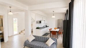 A modern living room with a sofa, dining area, kitchen, and staircase. - Zaffiri House - Elegant villa with private pool 300 mt from the sea (Plemmirio)