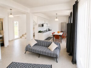 Ein modernes Wohnzimmer mit Sofa, Essbereich, Küche und Treppe.