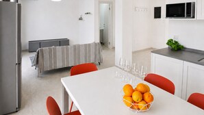 A modern kitchen with a dining area, a refrigerator, a microwave, and a table with a bowl of oranges. - Zaffiri House - Elegant villa with private pool 300 mt from the sea (Plemmirio)
