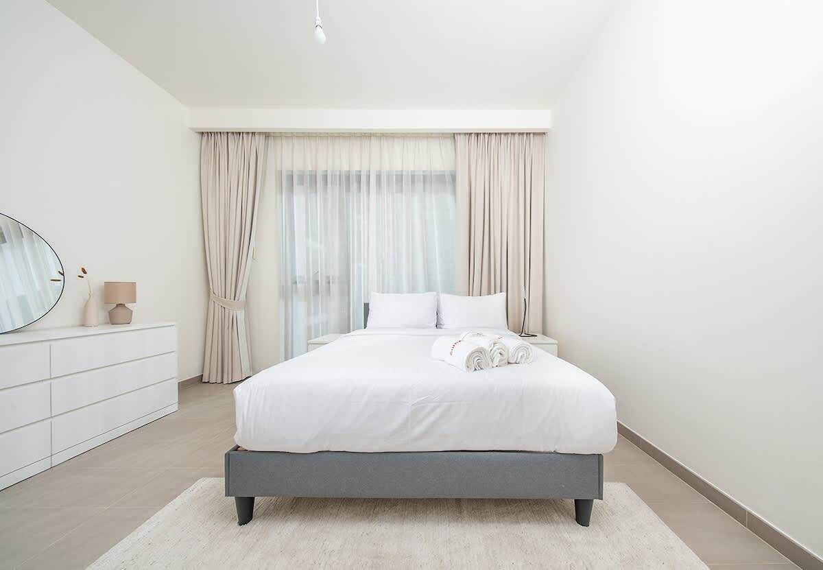 Une chambre à coucher moderne avec un lit, des rideaux, une table de chevet et un miroir.