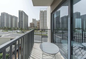Ein Balkon mit Tisch und Stühlen, mit Blick auf eine Stadtlandschaft mit Hochhäusern.