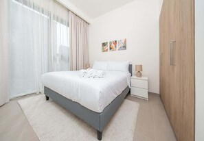 A modern bedroom with a bed, bedside tables, and a wardrobe. - Pool Access Modern Apartment in Park Ridge Dubai (Dubai)