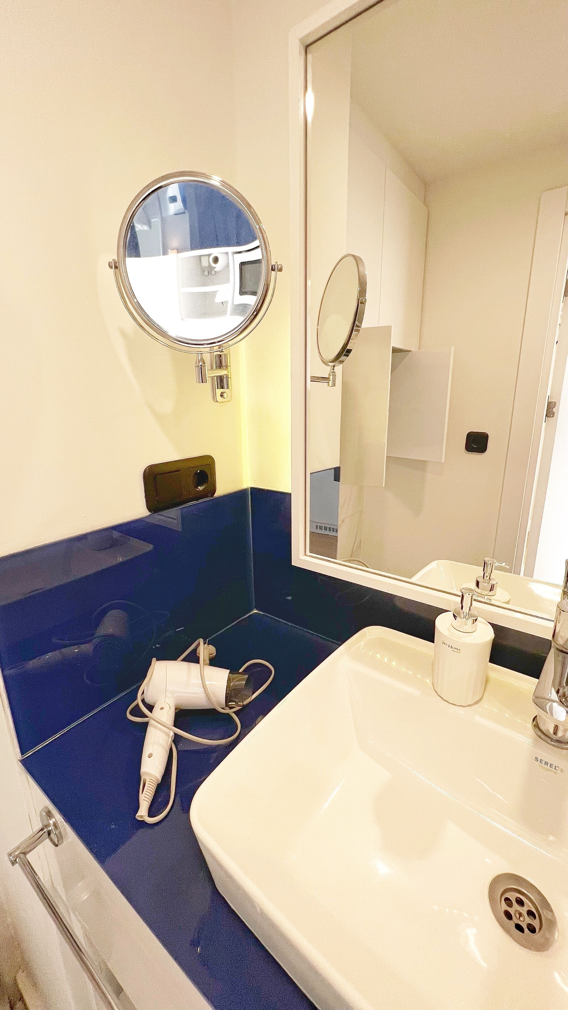 Une salle de bain avec un lavabo, un miroir et une baignoire bleue.