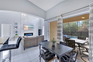 Ein modernes Wohnzimmer mit Fernseher, Sofa, Esstisch und Stühlen.