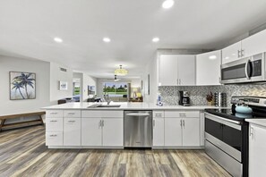 Une cuisine moderne avec des meubles blancs, des appareils en acier inoxydable et un grand îlot central.
