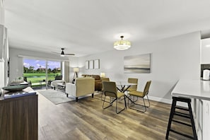 Un salon moderne avec un coin repas, un ventilateur de plafond et une vue sur un terrain de golf.