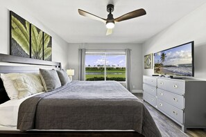 A bedroom with a bed, a ceiling fan, a TV, and a view of a golf course. - Updated 2BR/2BA Isla Del Sol Condo with Golf Course Views & Pool Near St. Pete Beach (Isla Del Sol)